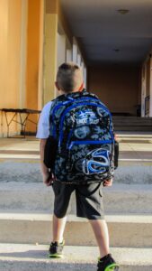 Lille dreng med skoletaske på ryggen på vej i skole